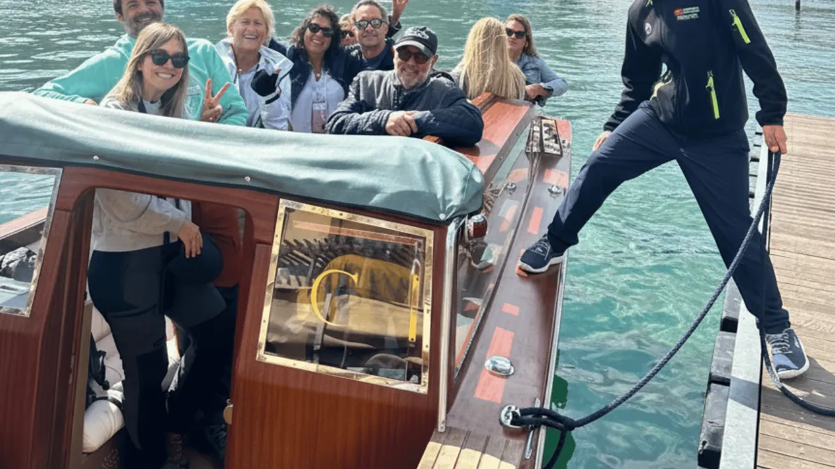 Venetian-style wooden taxi boat cruising past Villa Olmo on Lake Como